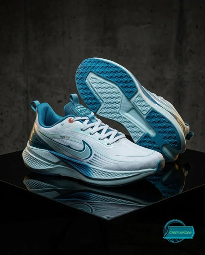 Light blue and white athletic sneakers with textured soles on a reflective black surface.